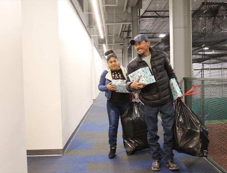 Two volunteers carrying large bags filled with gifts