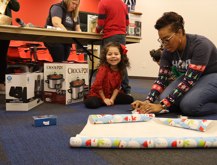 Adult and two young volunteers wrapping gifts together