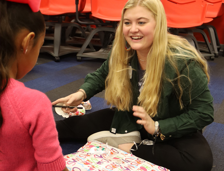 Team member talking to a young volunteer while wrapping gift