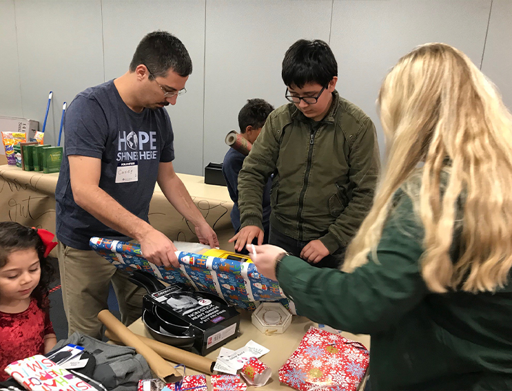 Team members and young volunteer gift wrapping