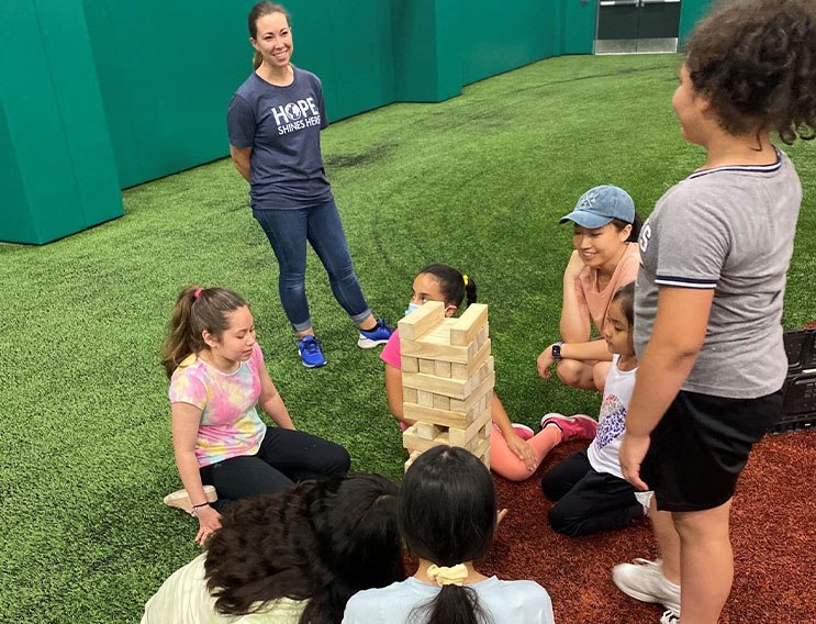 Team members and young volunteers playing block stacking game