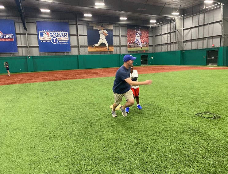 Team member and young person playing baseball