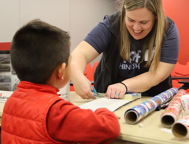 Team member and child wrapping gifts