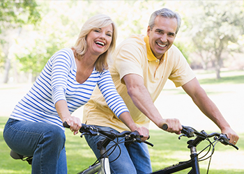 Smiling older man and woman on a bike ride after discussing wealth management in Irving Texas