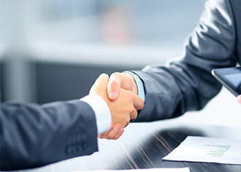 Two people shaking hands during asset management meeting