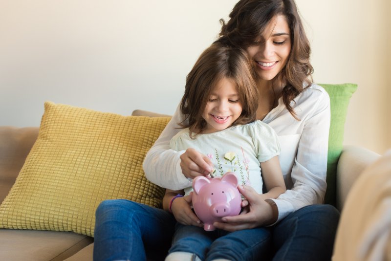 mother and daughter holding a pink piggy bank